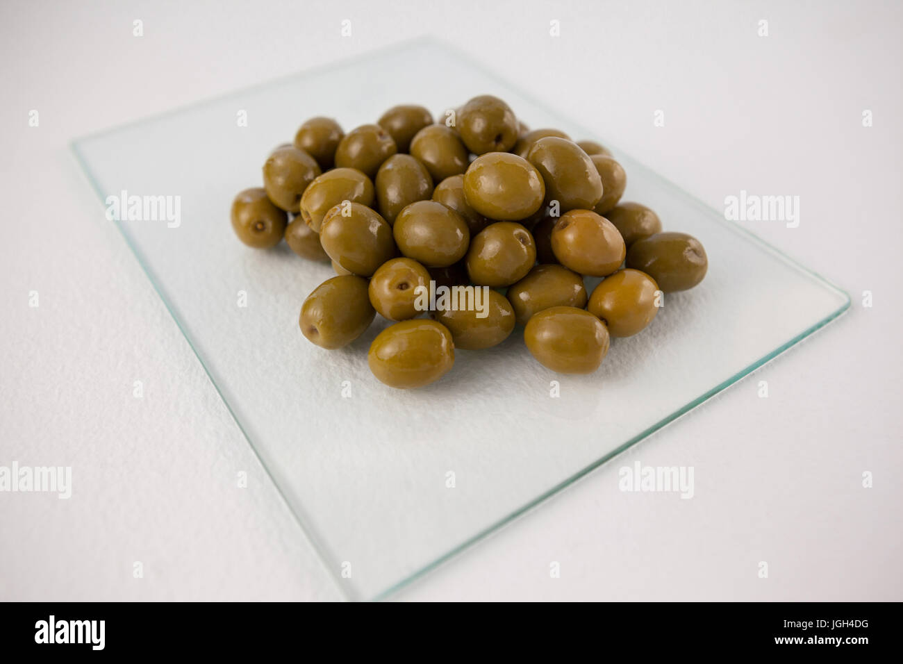 Close up of green olives sur dalle de verre à table Banque D'Images