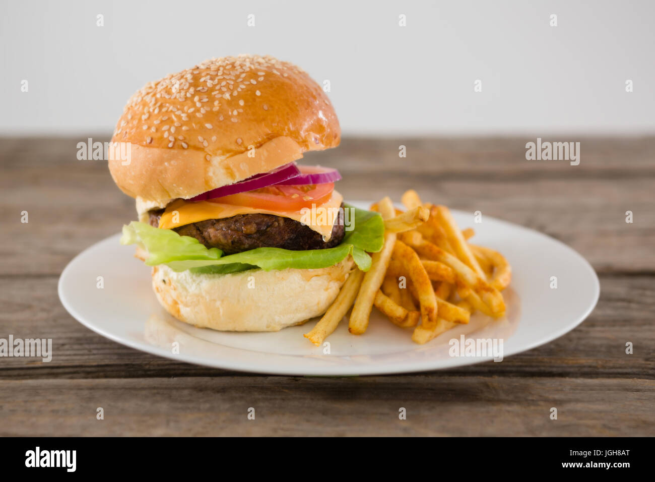 Cheeseburger accompagné de frites dans la plaque sur la table contre le mur Banque D'Images