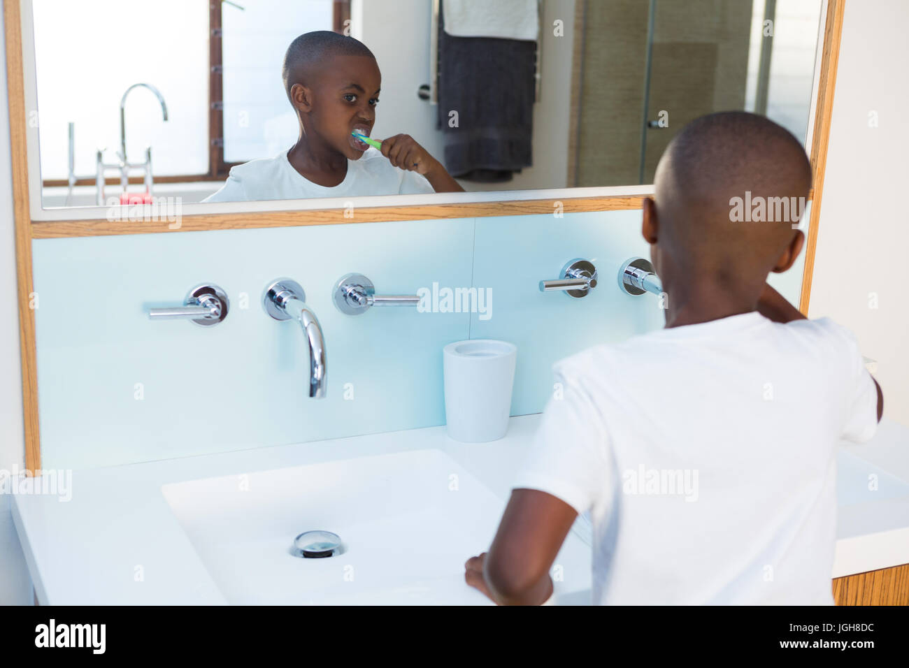 Garçon se brosser les dents à la réflexion au miroir de salle de bains intérieure Banque D'Images