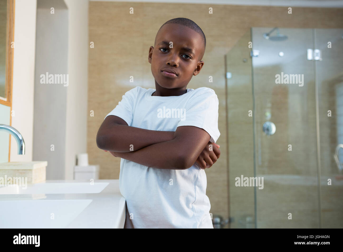Portrait of boy standing par lavabo avec les bras croisés à la salle de bains Banque D'Images