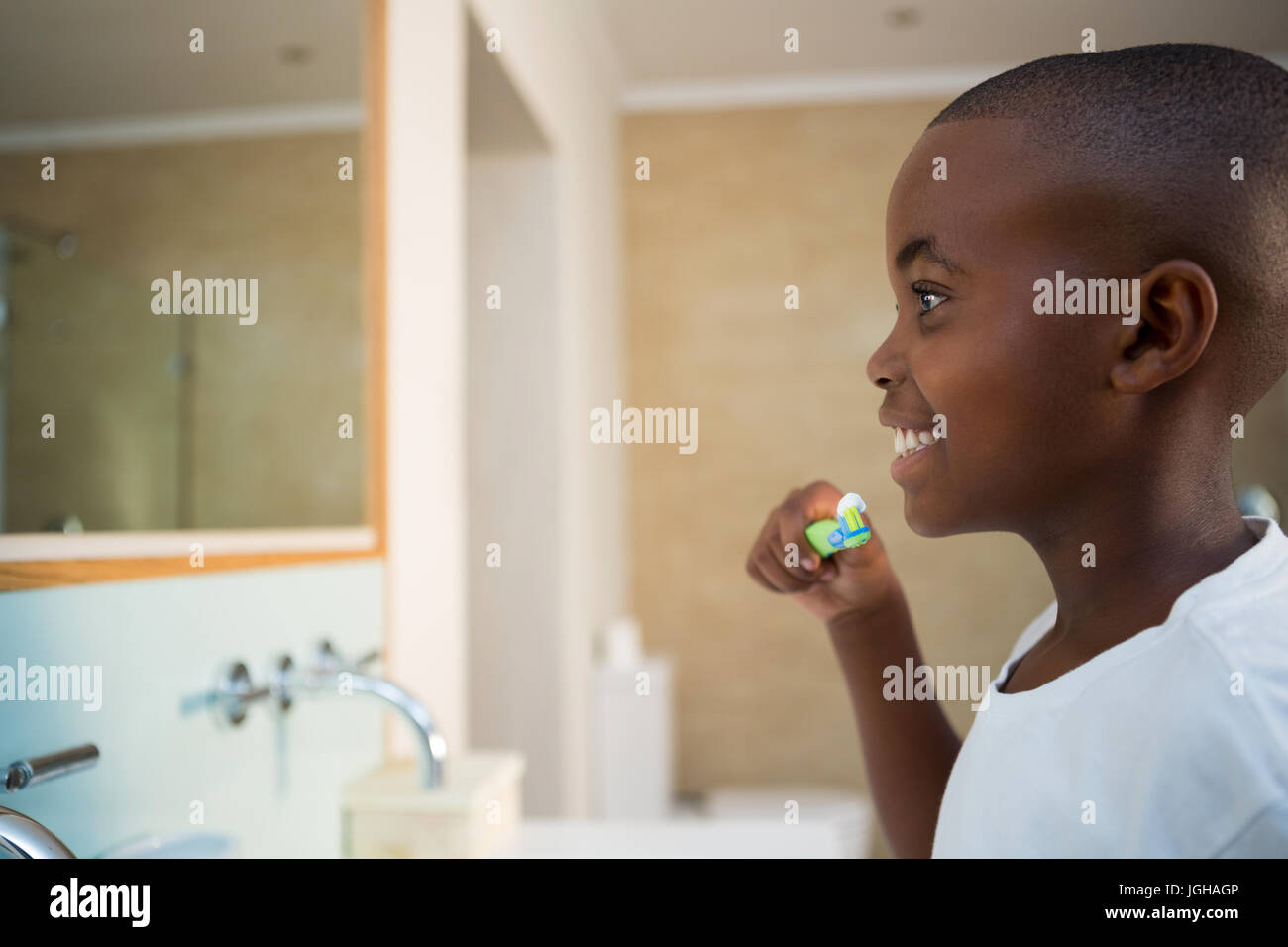 Vue latérale du smiling boy avec une brosse à dents dans la salle de bains intérieure Banque D'Images