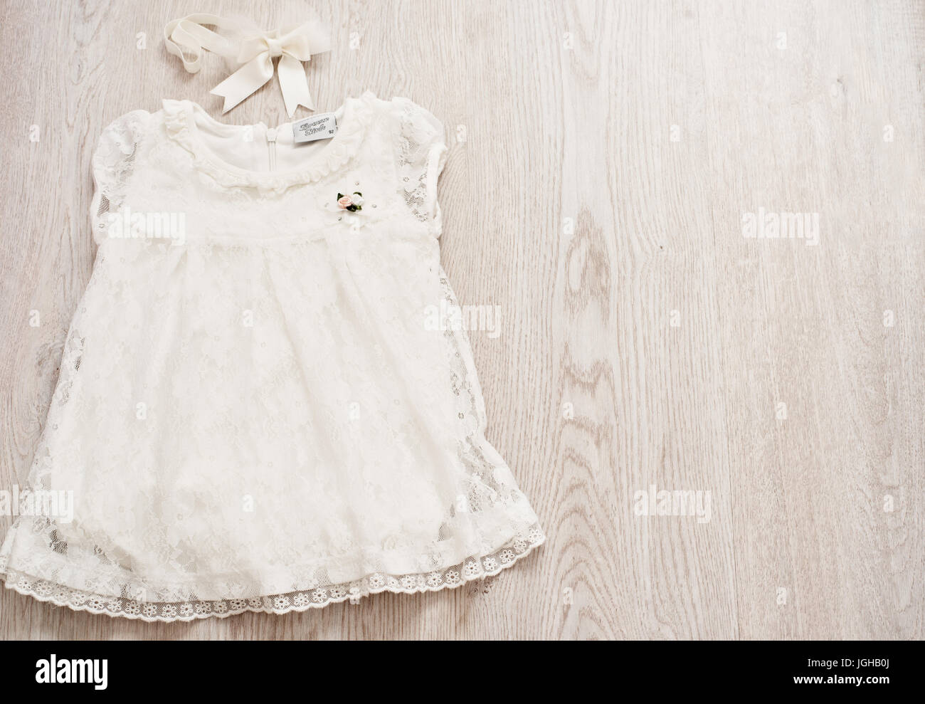 Bébé Vintage robe en dentelle blanche et Bow Headband gris clair sur un fond Wodden. Vue de dessus, Copy Space Banque D'Images