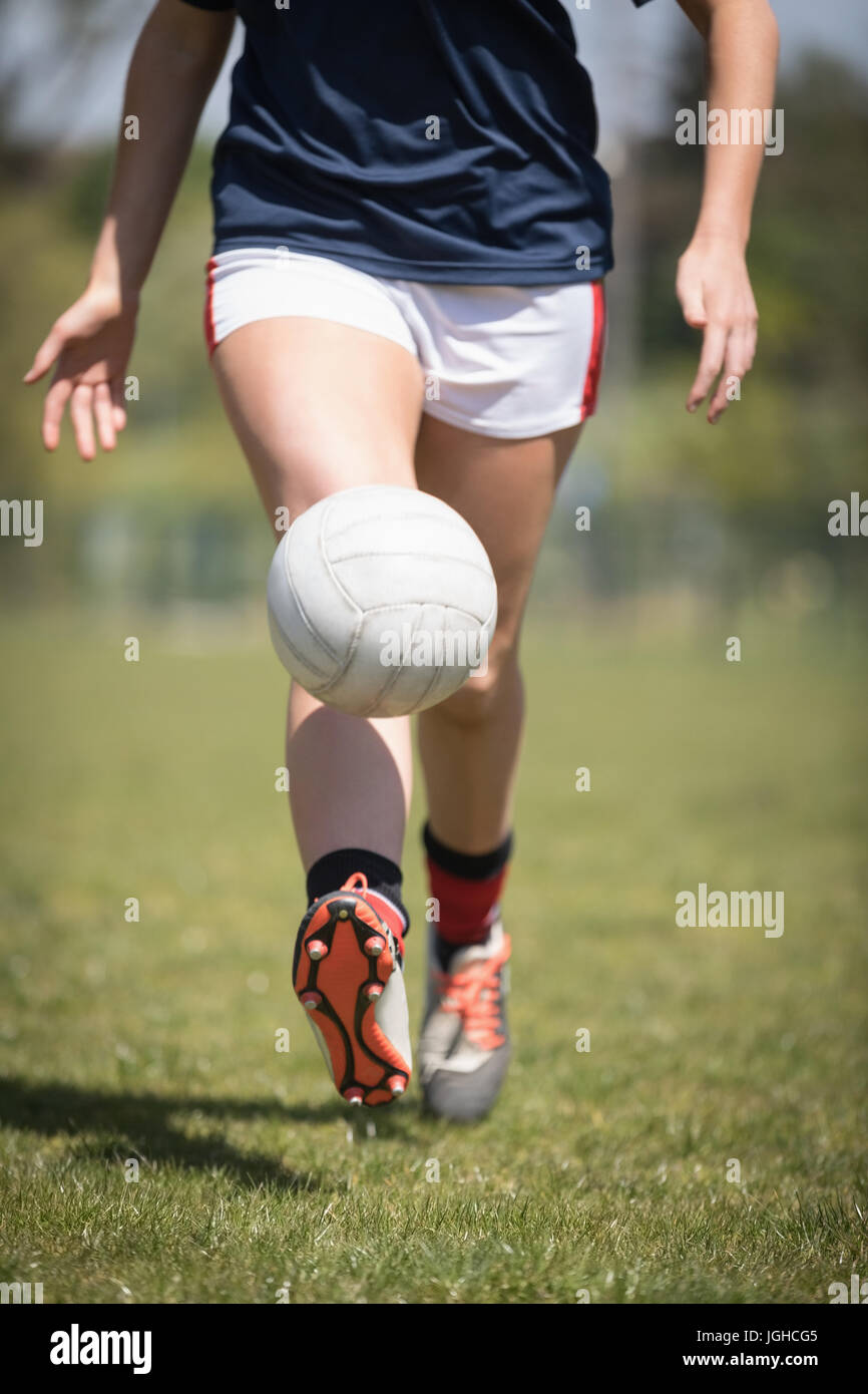 La section basse de femmes joueur de jouer avec un ballon de football sur terrain Banque D'Images