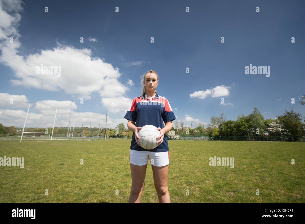 Female player holding soccer ball sur le terrain de jeu contre le ciel Banque D'Images