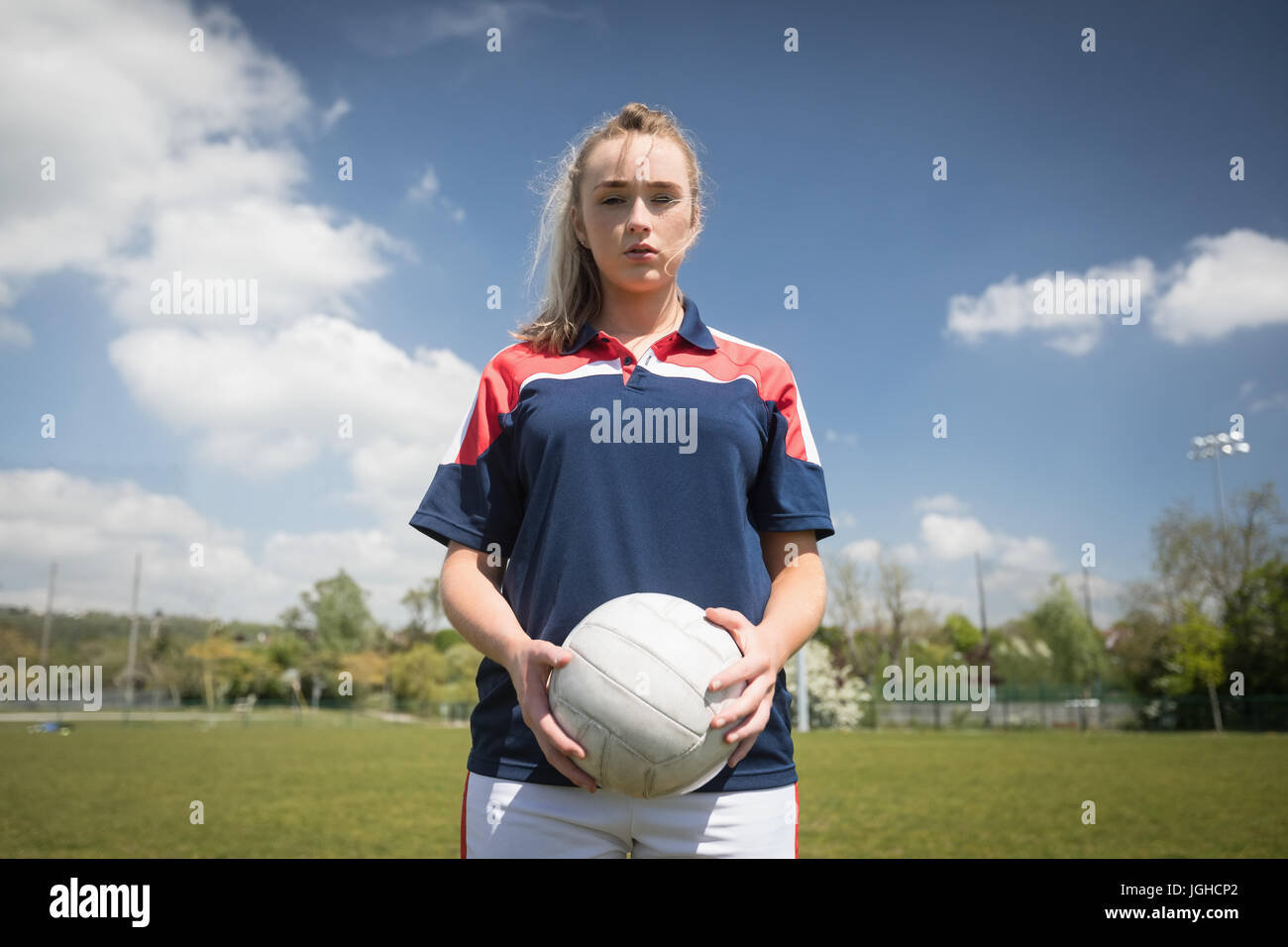 Portrait of female player holding soccer ball on field against sky Banque D'Images