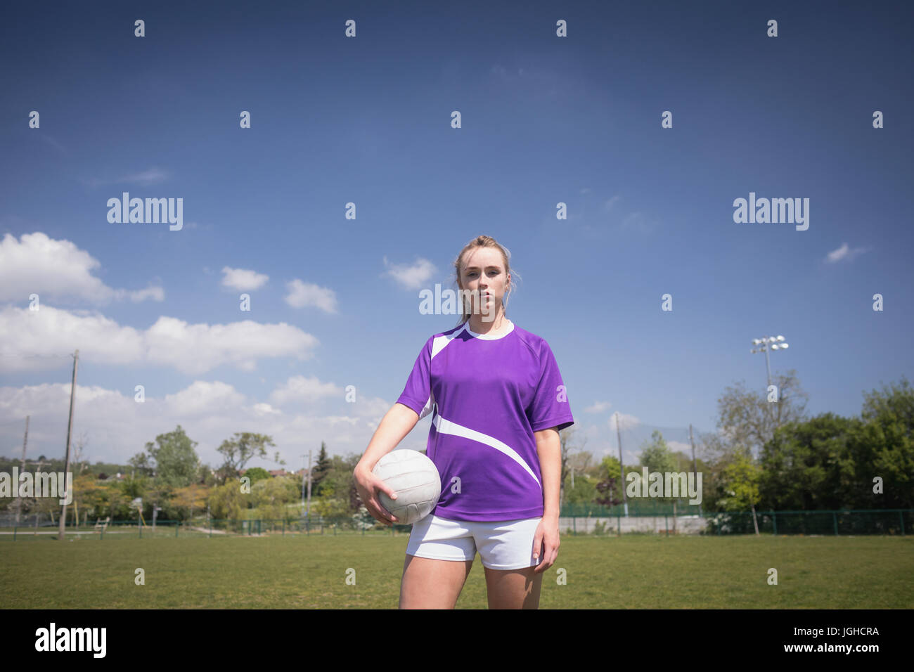 Portrait de femme avec ballon de foot ball debout sur domaine against sky Banque D'Images