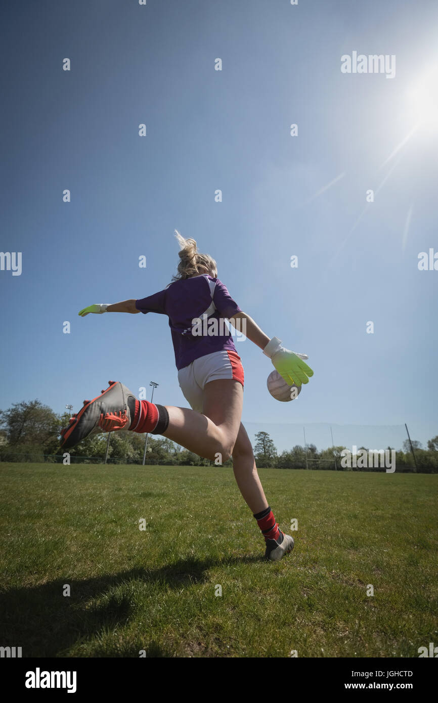 Vue arrière de la femme jouant au football sur terrain au cours de journée ensoleillée Banque D'Images