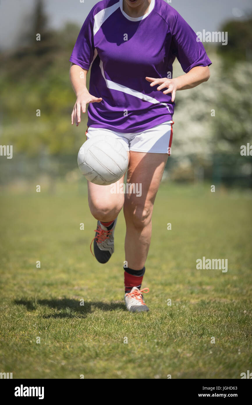 Jeune femme jouant au football sur terrain au cours de journée ensoleillée Banque D'Images