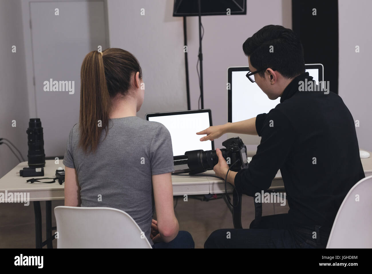 Assistant Photographe masculin expliquant lors de l'utilisation d'ordinateur portable au studio Banque D'Images