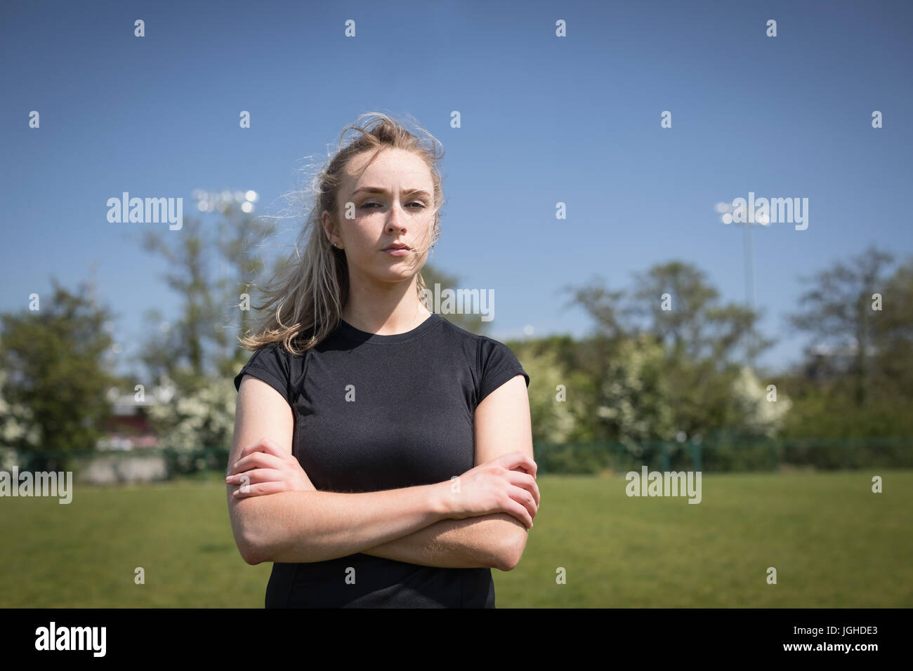 Portrait of female soccer player with arms crossed standing sur terrain de jeu Banque D'Images