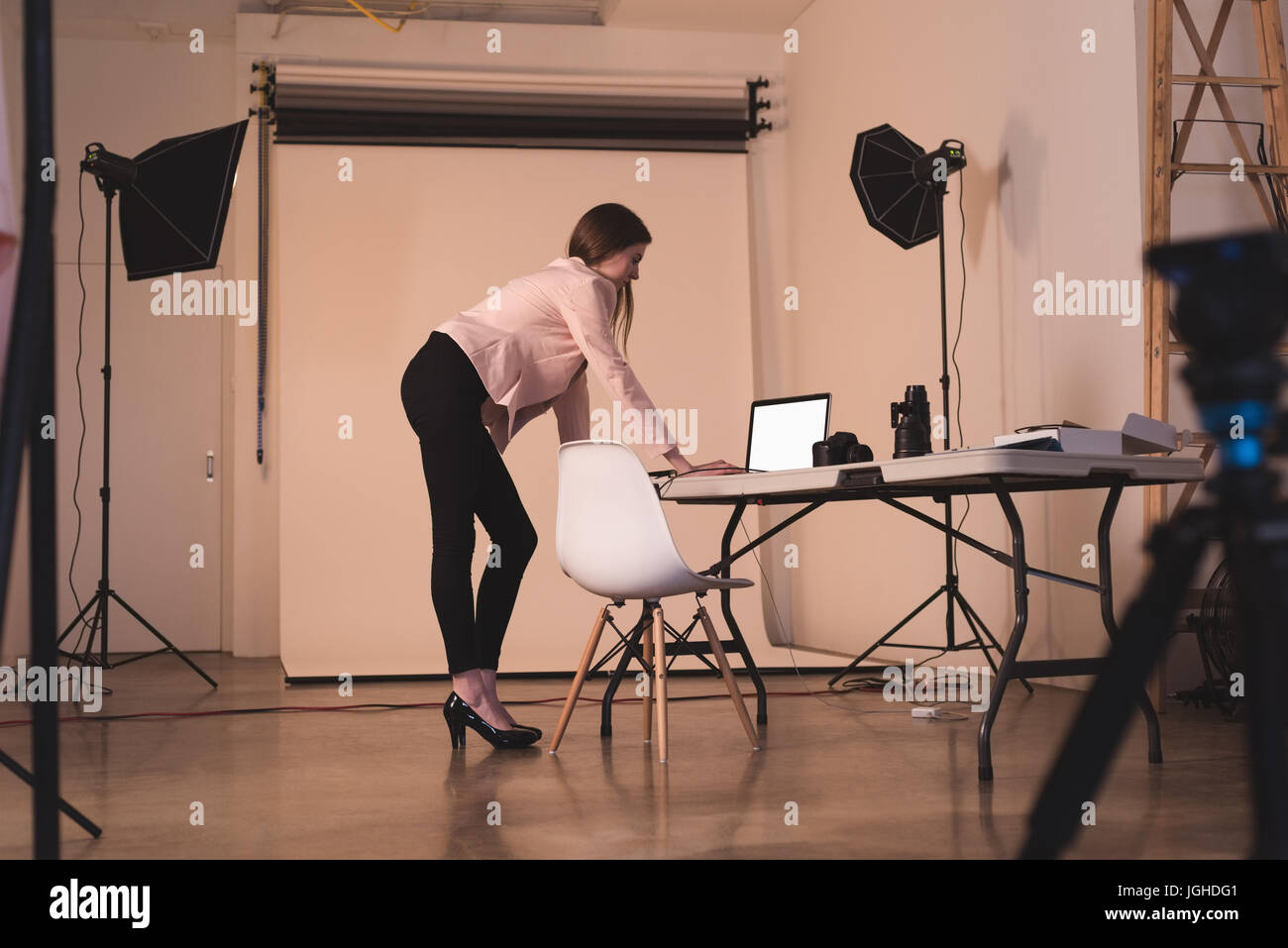 Toute la longueur du modèle féminin en utilisant le portable contre les toile au studio Banque D'Images