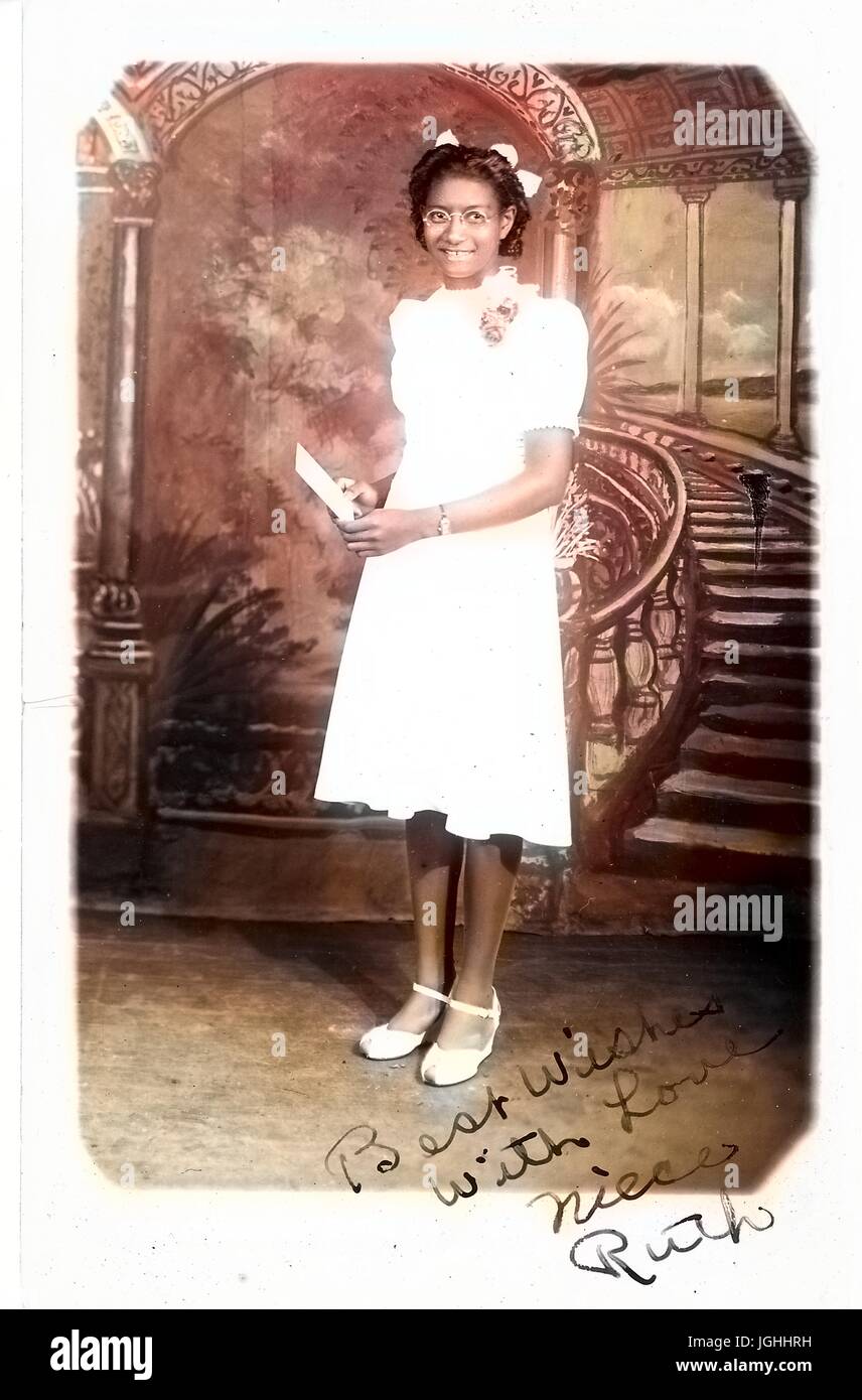 Portrait de jeune femme afro-américaine en blanc robe longueur genou, debout en face de Fresco, 1920. Remarque : l'image a été colorisée numériquement à l'aide d'un processus moderne. Les couleurs peuvent ne pas être exacts à l'autre. Banque D'Images