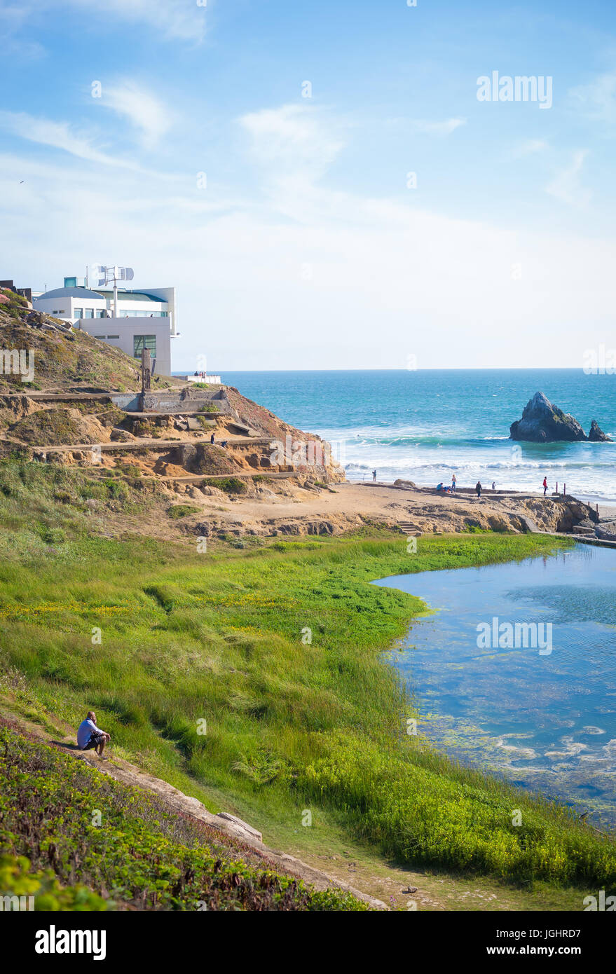 Homme assis sur un terrain herbeux, regardant vers les bains de sutro. Banque D'Images