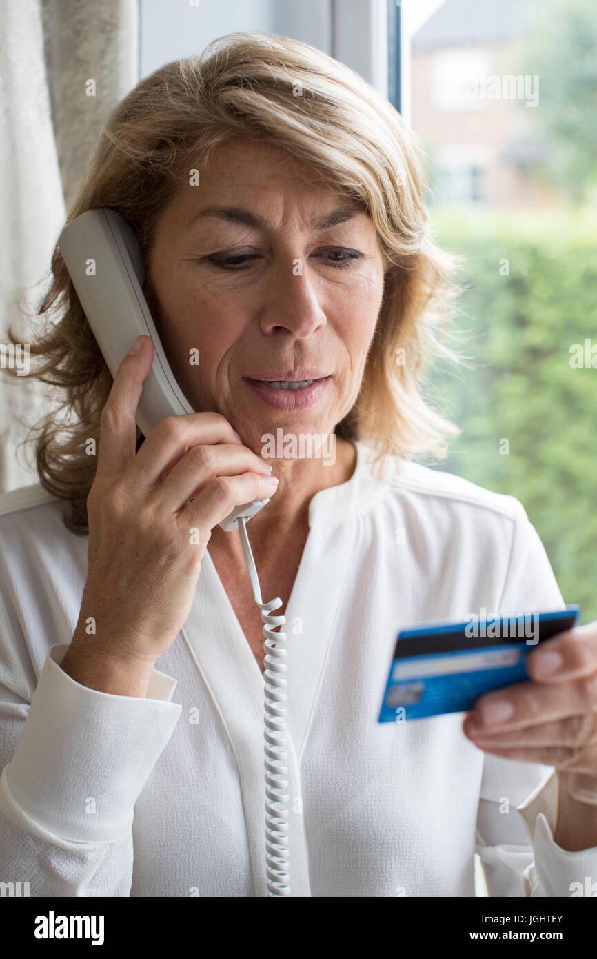 Femme mature en donnant des détails de carte de crédit au téléphone Banque D'Images