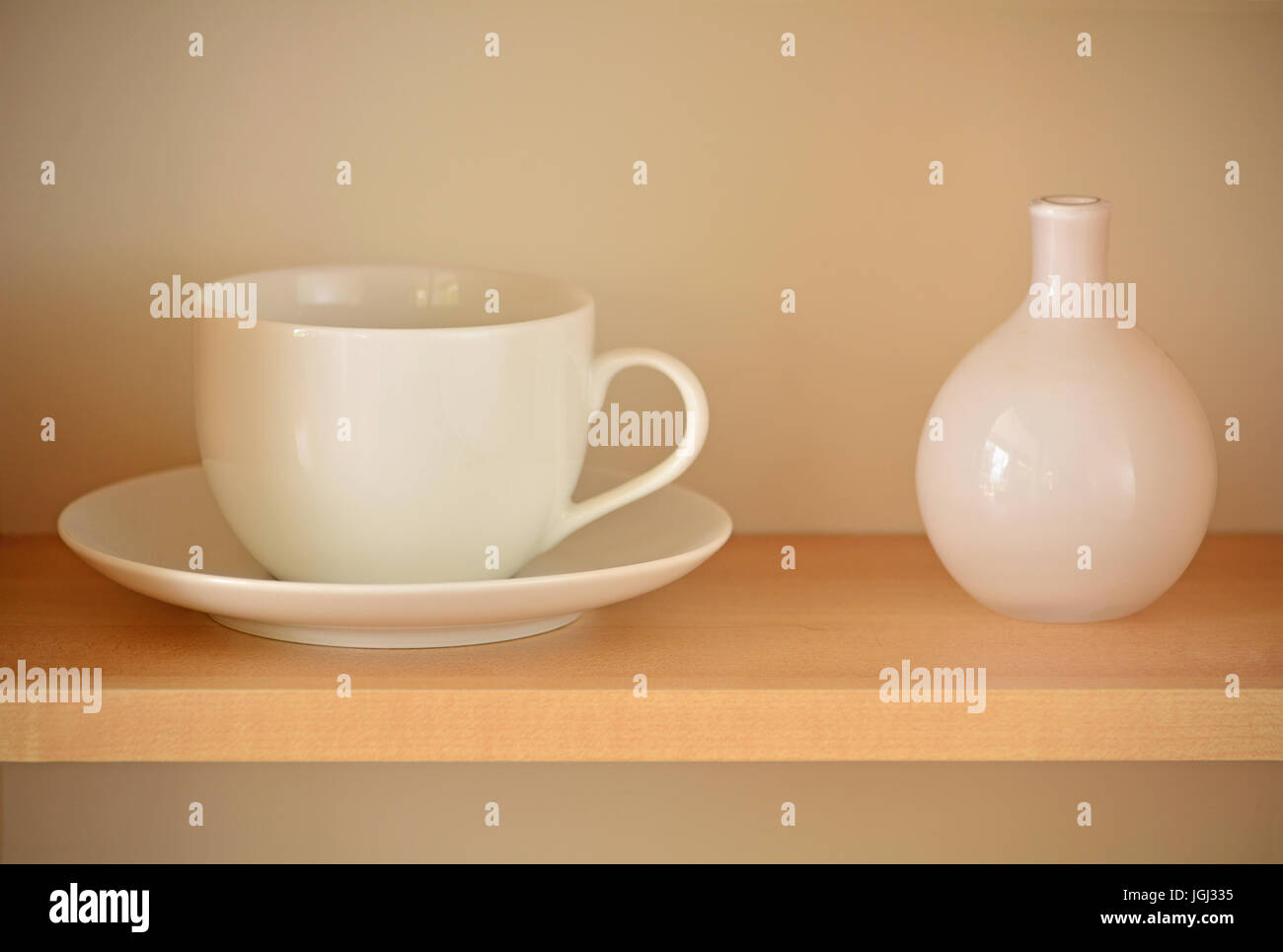 Tasse et soucoupe thé blanc avec petit vase blanc sur planche en bois. Format horizontal avec focus sélectif. Banque D'Images