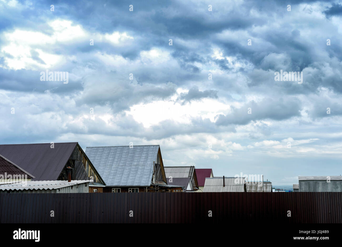 Metal toits de maisons du village sur un fond de nuage orageux Banque D'Images
