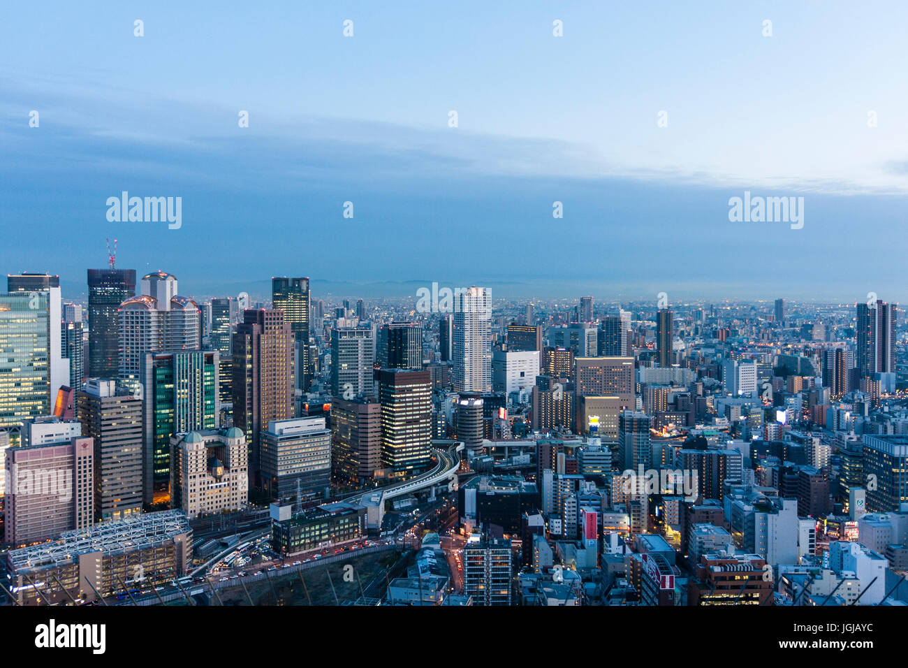 La Ville d'Osaka, au Japon. Crépuscule du soir high angle vue du haut des gratte-ciel Umeda. De tours de bureaux avec des montagnes en arrière-plan. Banque D'Images