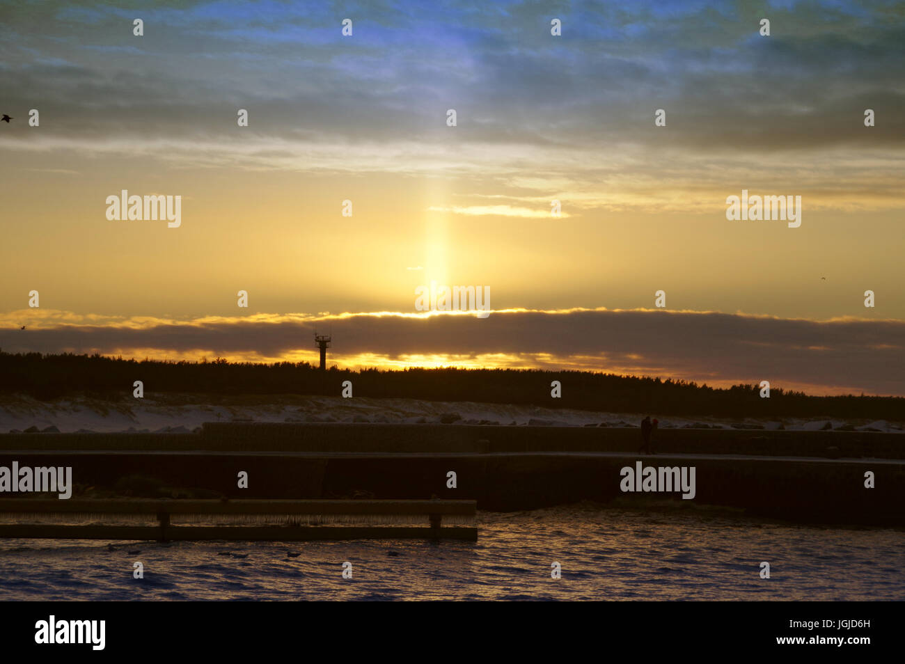 Pilier de lumière phénomène optique atmosphérique sur le coucher du soleil par la mer en hiver Banque D'Images