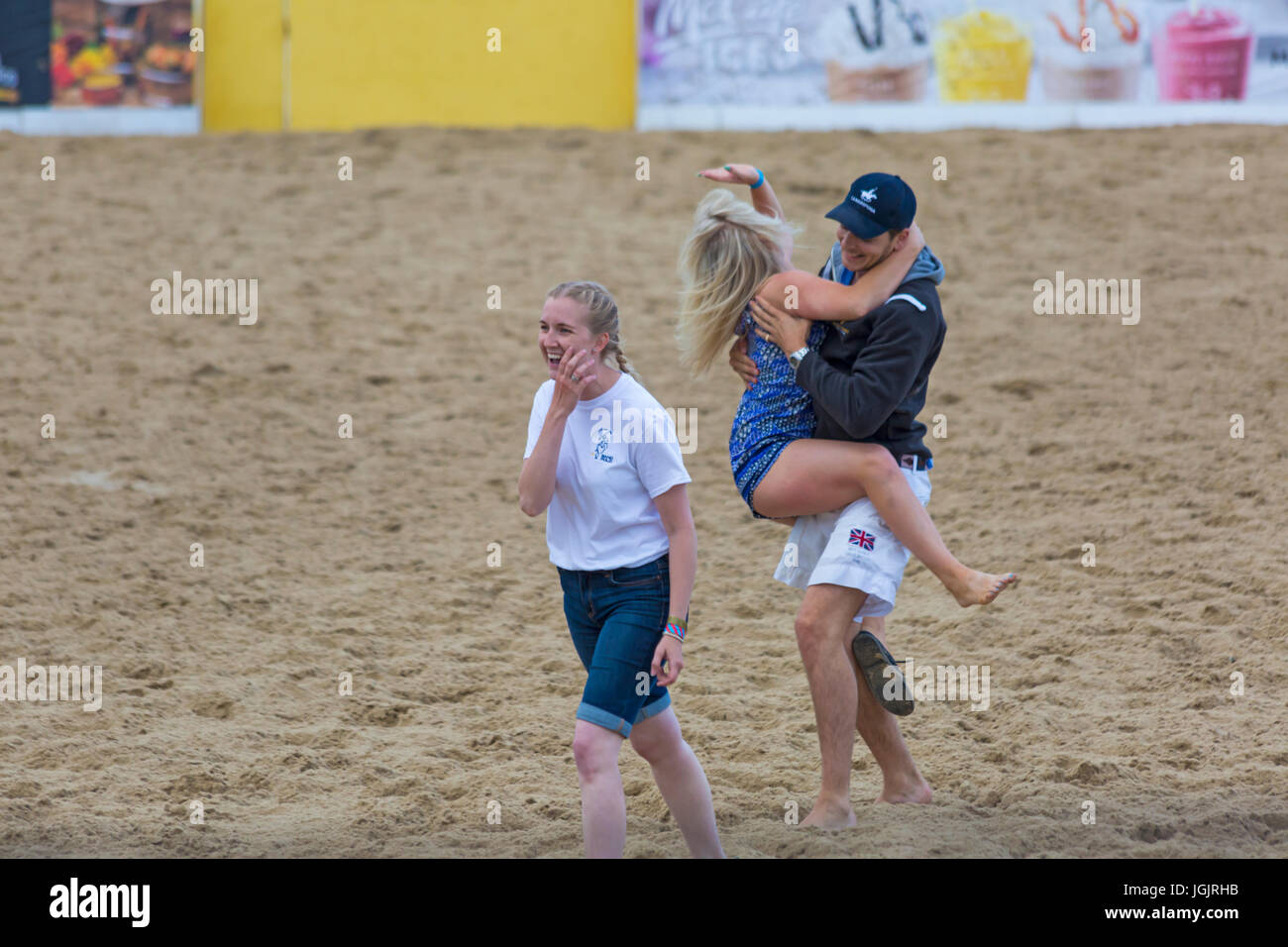 Bancs, Poole, Dorset, UK. 7 juillet, 2017. Les Britanniques Beach Polo Championships se met en route à la plage de Sandbanks, Poole. Les deux jours de l'événement a lieu le vendredi et samedi, en tant que visiteurs, chef de la plage pour voir l'action sur un jour ensoleillé chaud chaud. Jeune femme court vers l'arène de sable et 'amuse' la foule lors d'une pause dans le polo avant d'être retiré par la sécurité. Credit : Carolyn Jenkins/Alamy Live News Banque D'Images