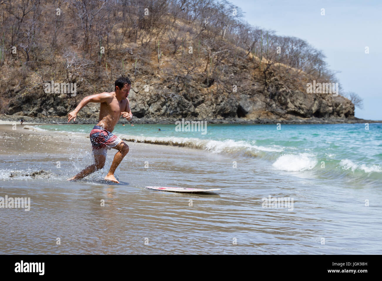 Jeune homme d'embarquement écrémé à Playa Calzon de Pobre, Costa Rica sur une belle journée ensoleillée. Banque D'Images