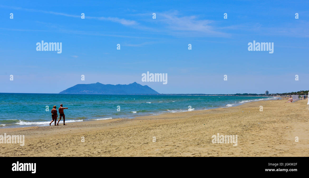 Deux personnes marchant le long de la plage de sable de la Méditerranée presque déserté, en Italie. Banque D'Images