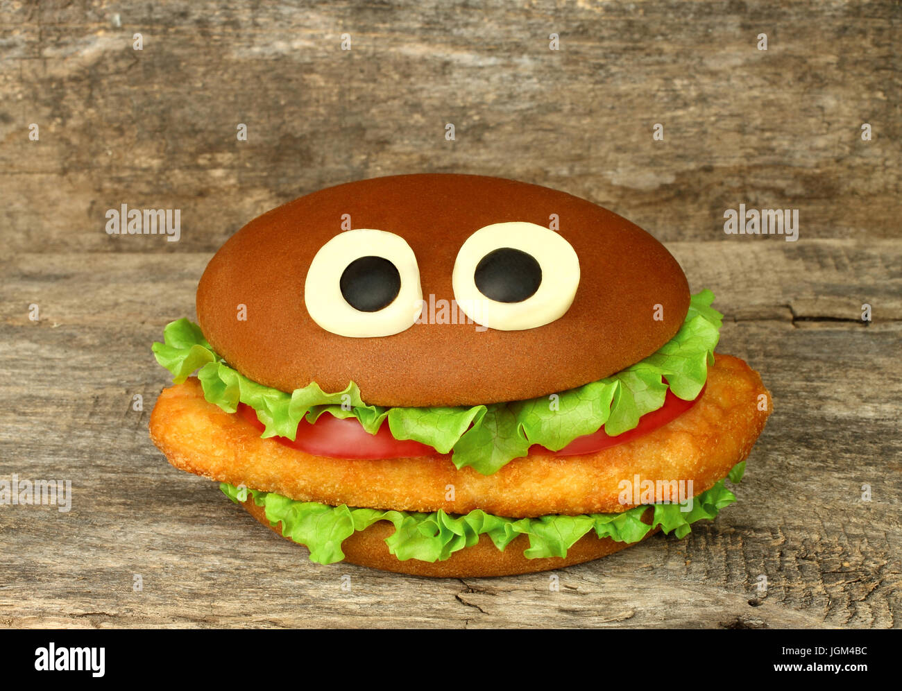 Funny Big hamburger au fromage avec les yeux et sur fond de bois escalope de poulet Banque D'Images