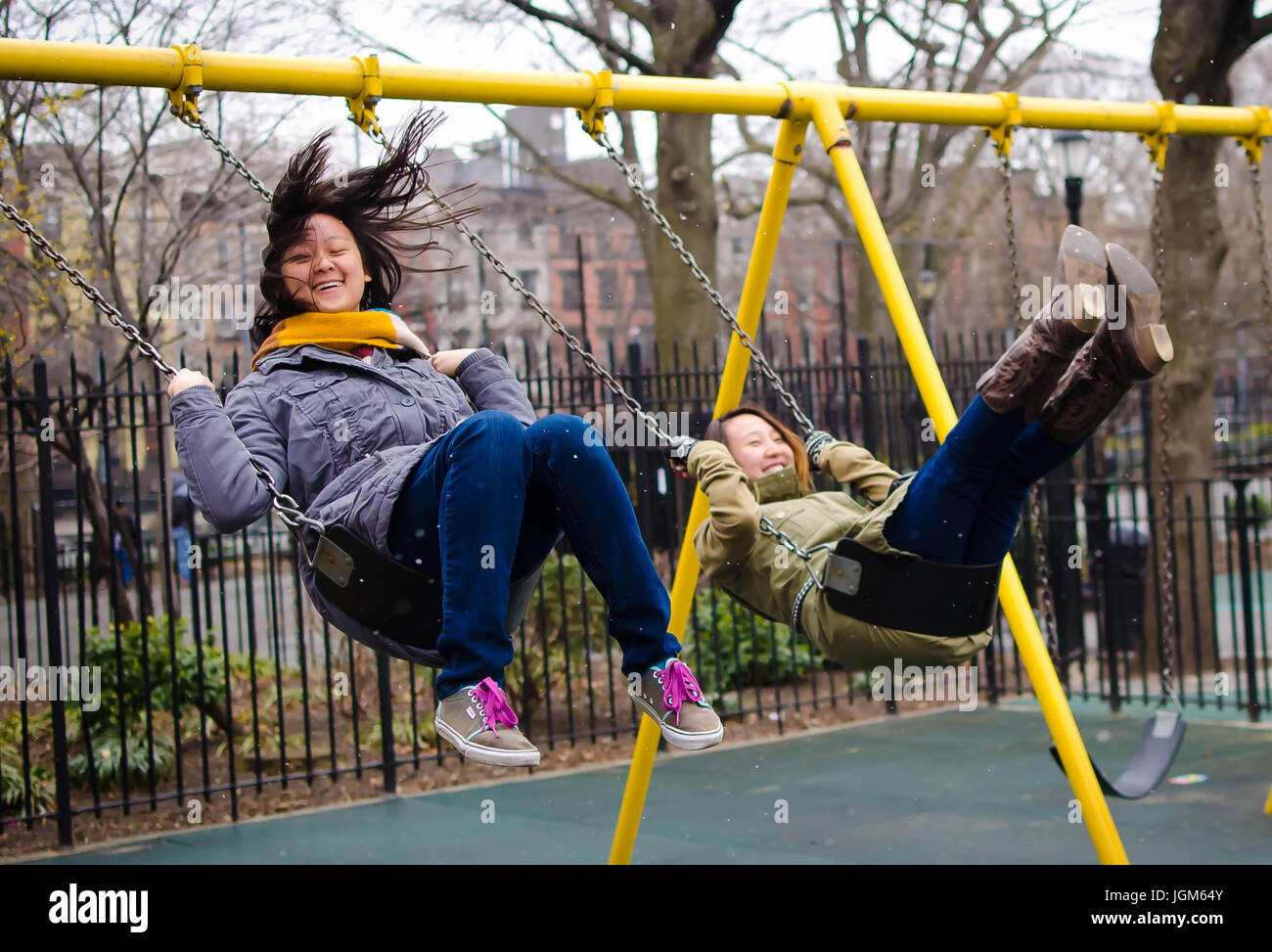 2 college kids swinging sur un swingset à New York City Banque D'Images