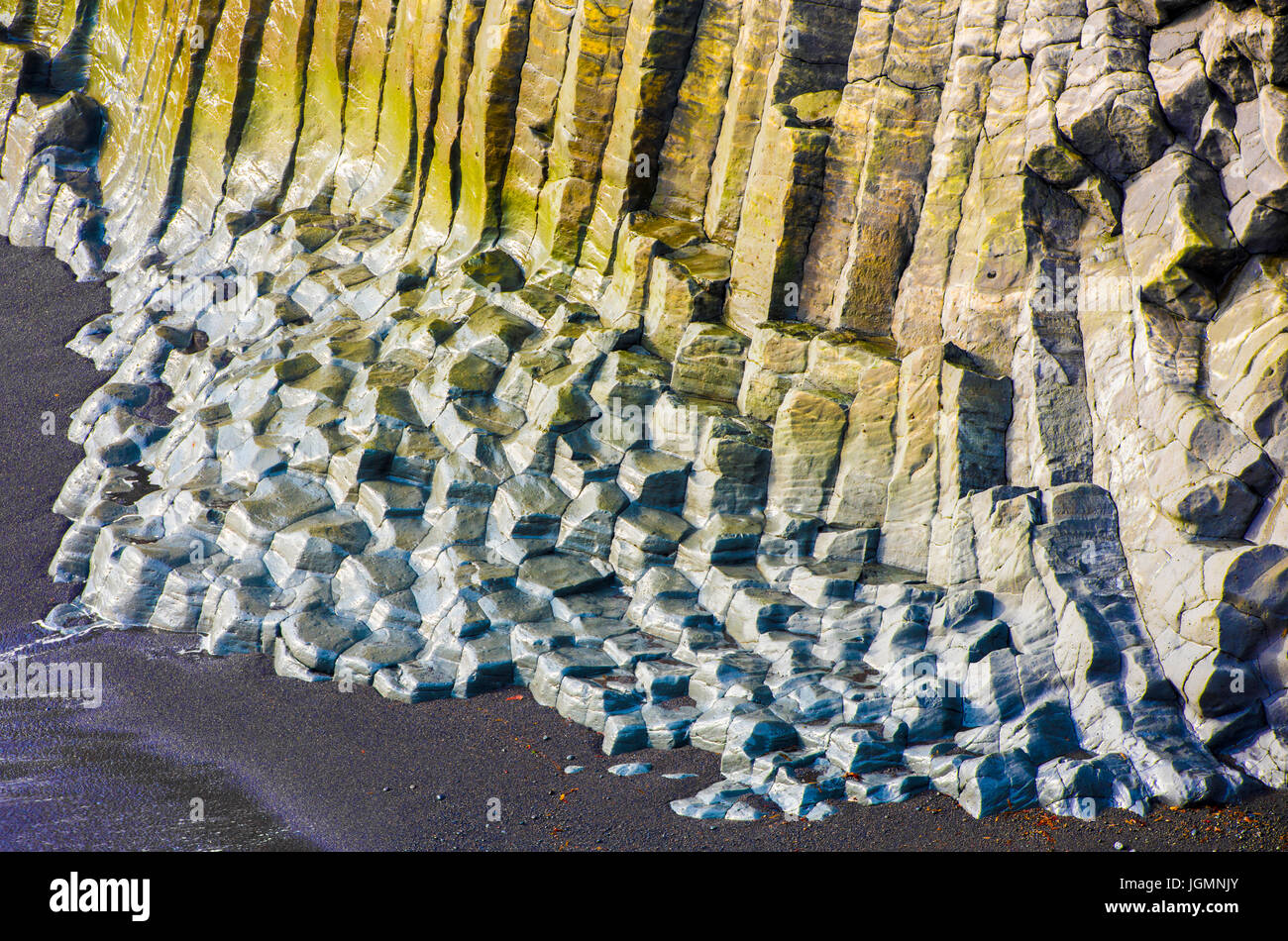 Gros rochers basaltiques avec mousse jaune et bleu sur la plage Banque D'Images