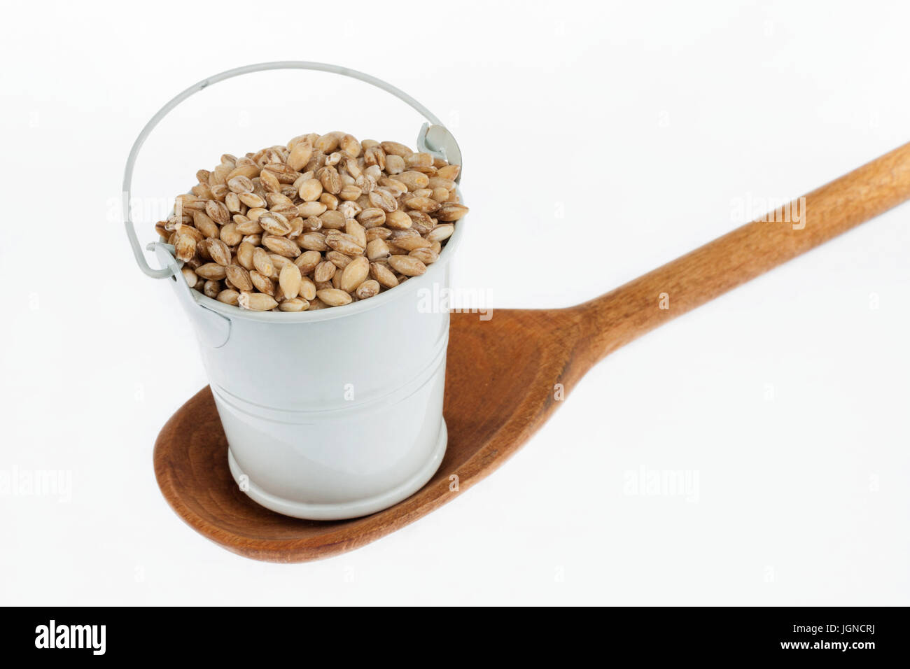 Godet plein de grains d'orge perle se trouve dans une cuillère en bois. Le concept de l'alimentation. Banque D'Images