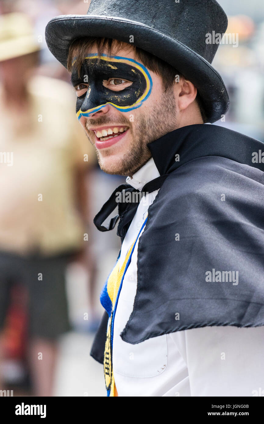 Jeune homme en costume, Yateley Morris, avec visage peint en forme de masque de bandit, 379, se tourna pour regarder en direction de téléspectateurs, pas de contact visuel, de sourire. Banque D'Images