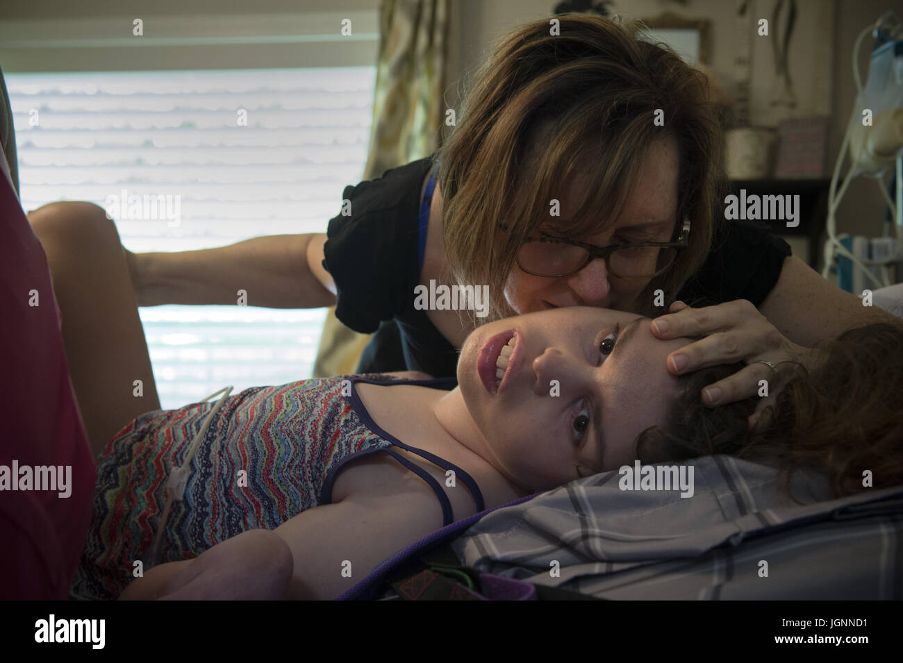 Comer, GA, USA. 5 juillet, 2017. Pam Walley et sa fille Callie's caregiver Lori Cain font de leur mieux pour stabiliser la jambe de Callie après son fémur cassé pendant qu'on la propose dans son lit. Callie a la paralysie cérébrale et est incapable de parler ou de marcher. À 22 ans, elle est soigné à la maison, avec l'aide des infirmières et d'aides, financées en partie par une renonciation de Medicaid qui aide les familles et les personnes handicapées - survivre et réussir --- en communauté plutôt que d'institutions. Crédit : Robin Rayne Nelson/ZUMA/Alamy Fil Live News Banque D'Images