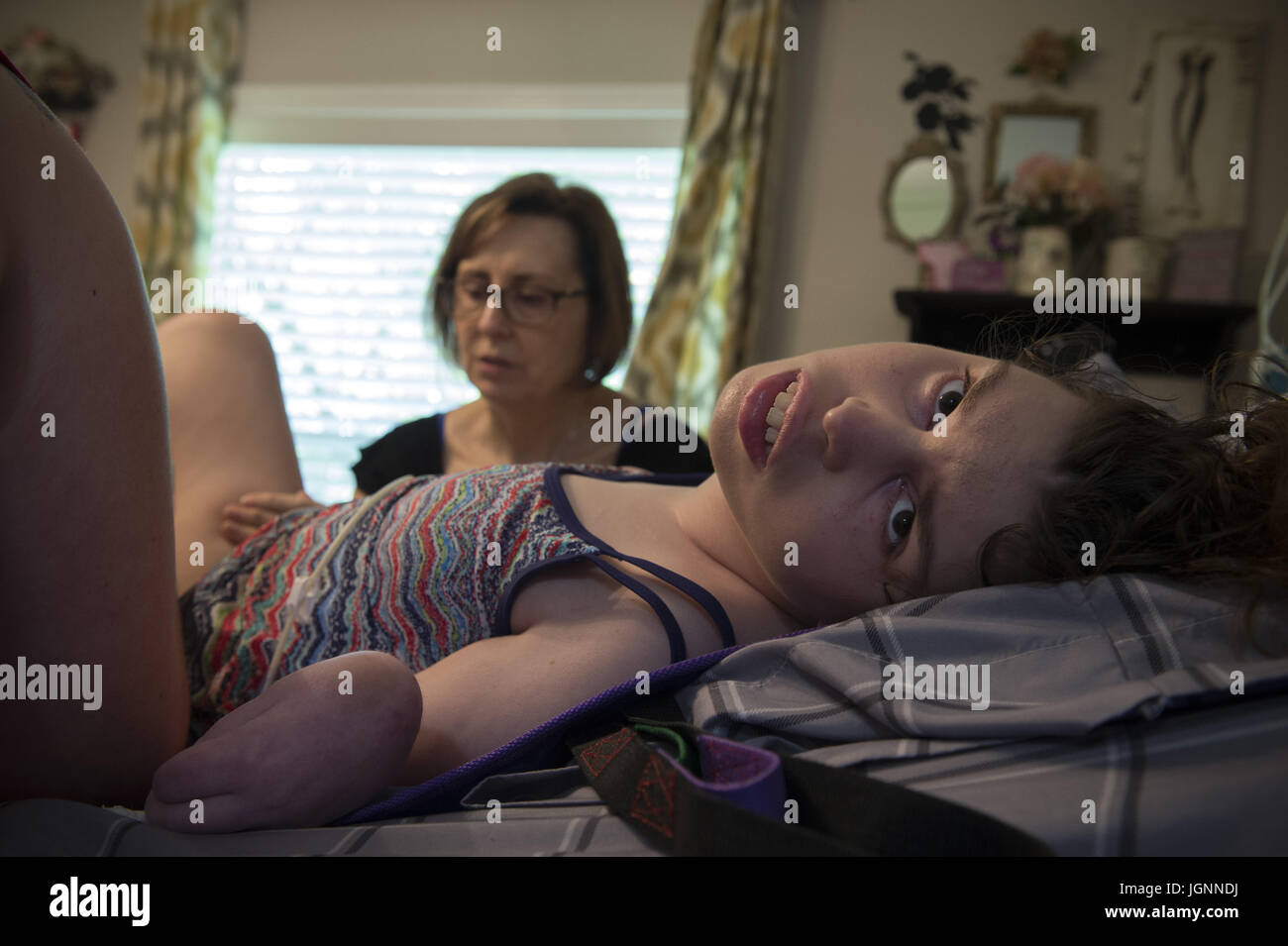 Comer, GA, USA. 5 juillet, 2017. Pam Walley et sa fille Callie's caregiver Lori Cain font de leur mieux pour stabiliser la jambe de Callie après son fémur cassé pendant qu'on la propose dans son lit. Callie a la paralysie cérébrale et est incapable de parler ou de marcher. À 22 ans, elle est soigné à la maison, avec l'aide des infirmières et d'aides, financées en partie par une renonciation de Medicaid qui aide les familles et les personnes handicapées - survivre et réussir --- en communauté plutôt que d'institutions. Crédit : Robin Rayne Nelson/ZUMA/Alamy Fil Live News Banque D'Images