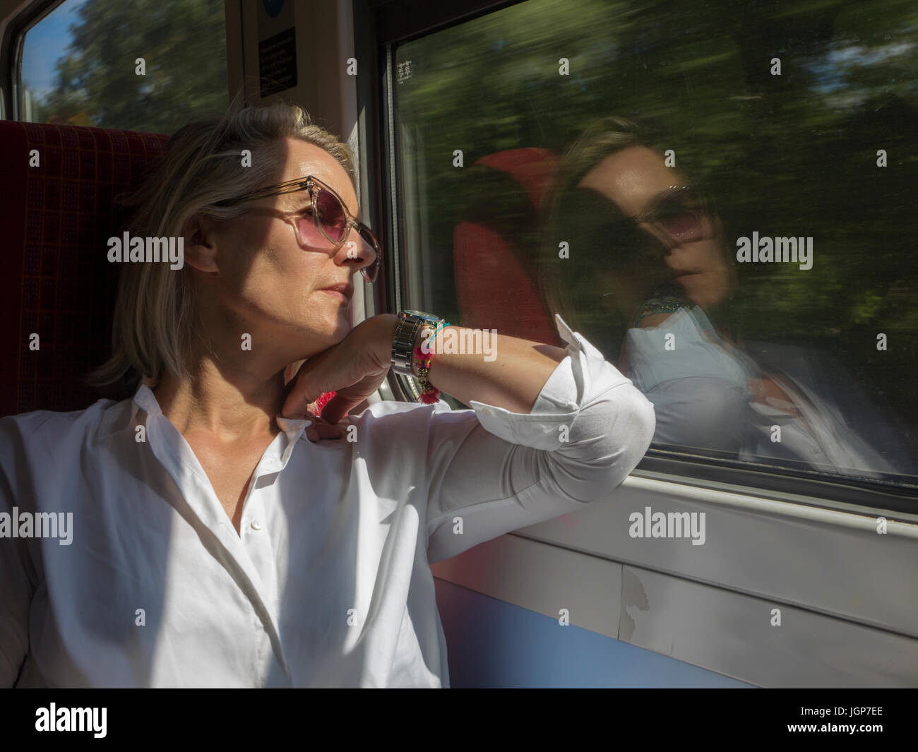 Une femme d'âge moyen n'envisage sur un voyage en train Banque D'Images
