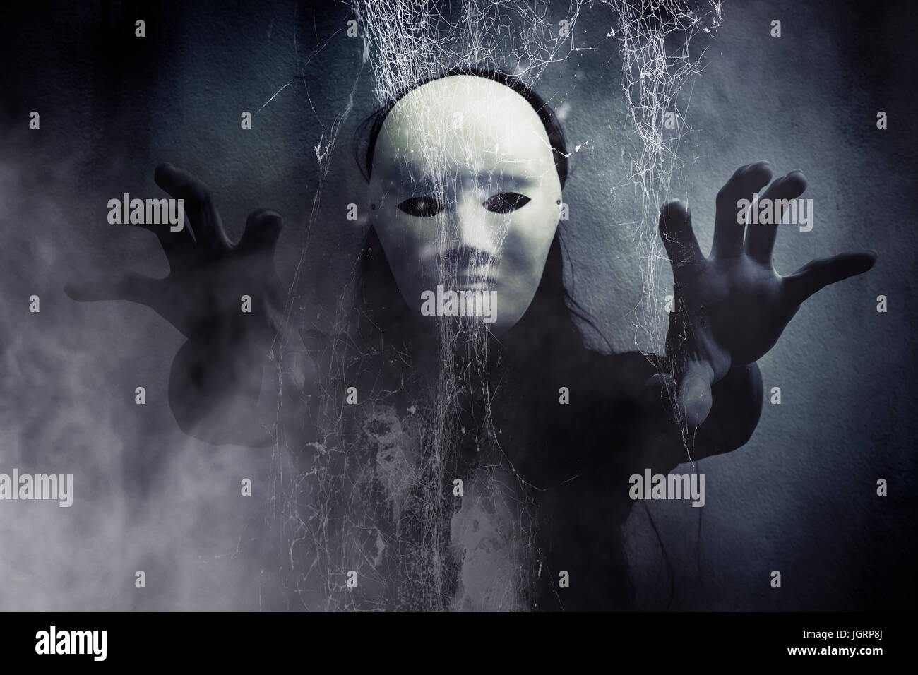 Mystérieuse femme en noir portant un masque blanc caché derrière spider web,fond effrayant pour couverture de livre Banque D'Images