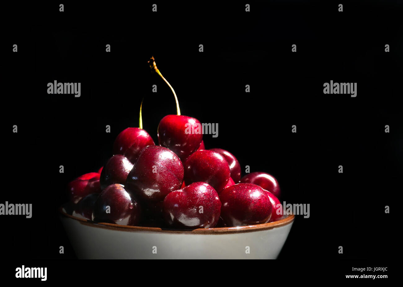 Cerises sur un fond noir. Les cerises mûres dans la plaque Banque D'Images