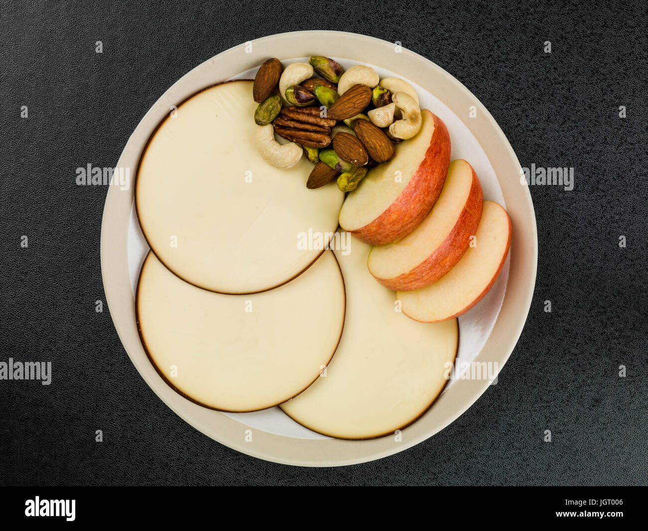 Les tranches de pommes et de fromage gouda rounds contre un fond noir Banque D'Images