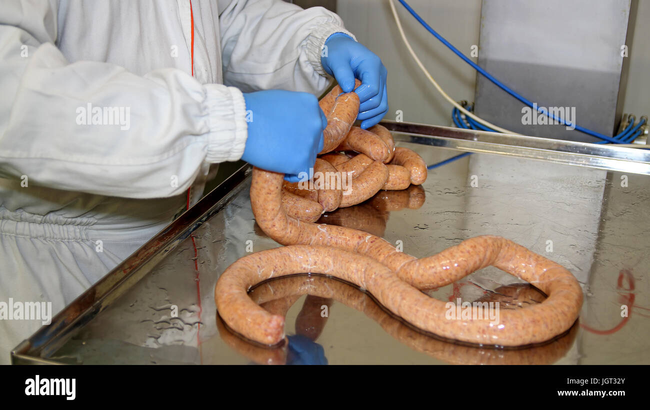 Des travailleurs les saucisses crues dans l'industrie de la viande. La production industrielle de saucisses. Banque D'Images