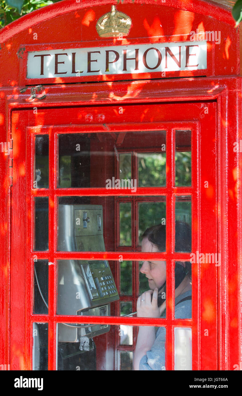 K6 téléphone fort. Femme à l'aide du téléphone dans un vieux BT K6 téléphone fort qui a récemment été peinte, au Royaume-Uni. Banque D'Images