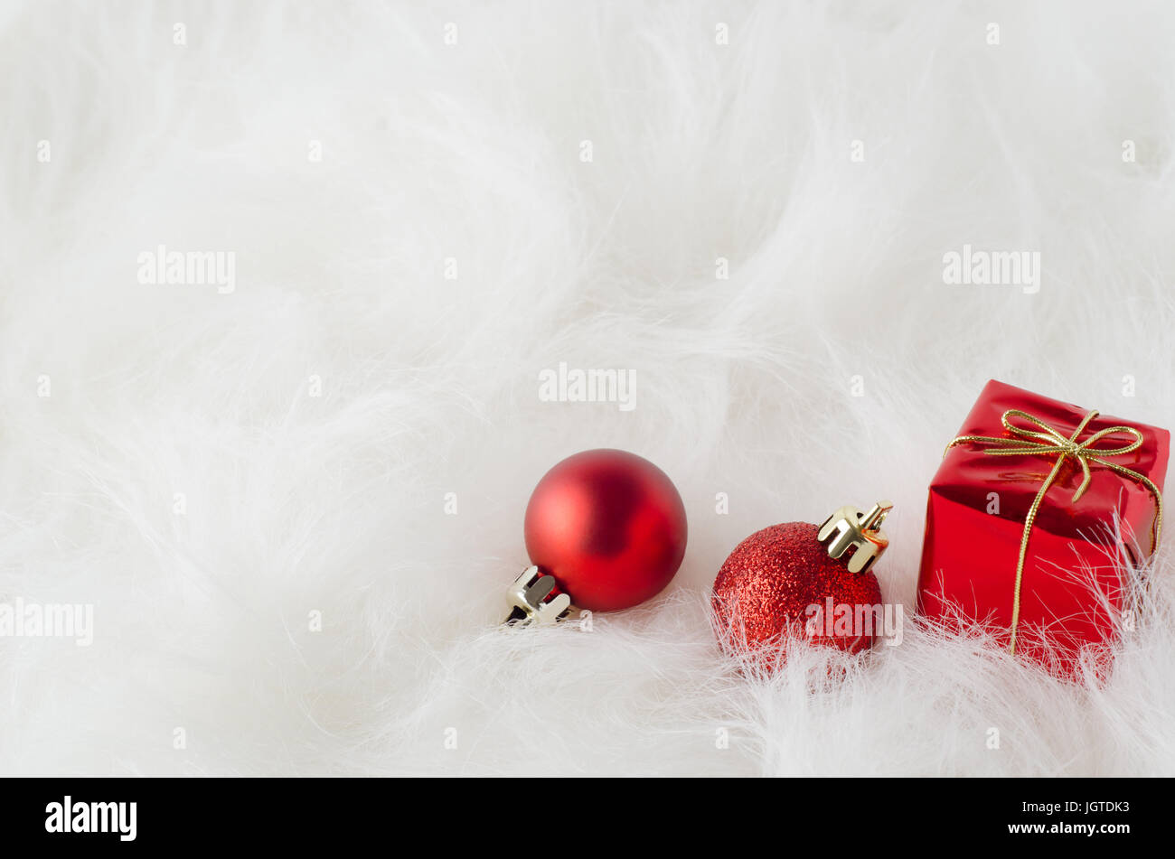 Red Christmas Ornaments on Snowy White fausse fourrure, niché dans le coin inférieur droit avec copie espace à gauche et ci-dessus. Banque D'Images