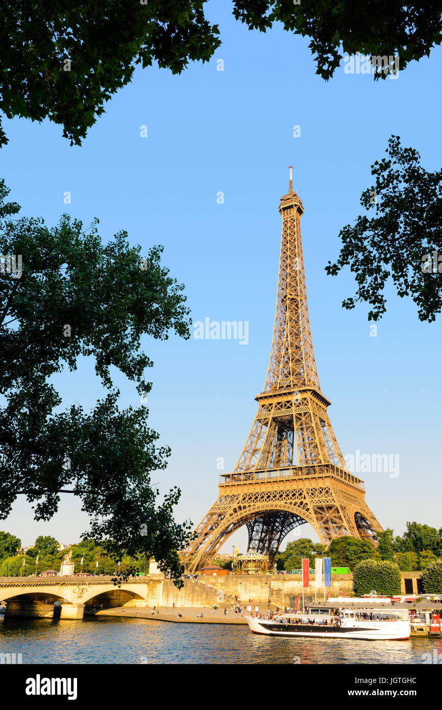 La Tour Eiffel à Paris, France, vu depuis le quai Debilly au coucher du soleil avec le pont d'Iéna et de la Seine et des navettes touristiques. Banque D'Images