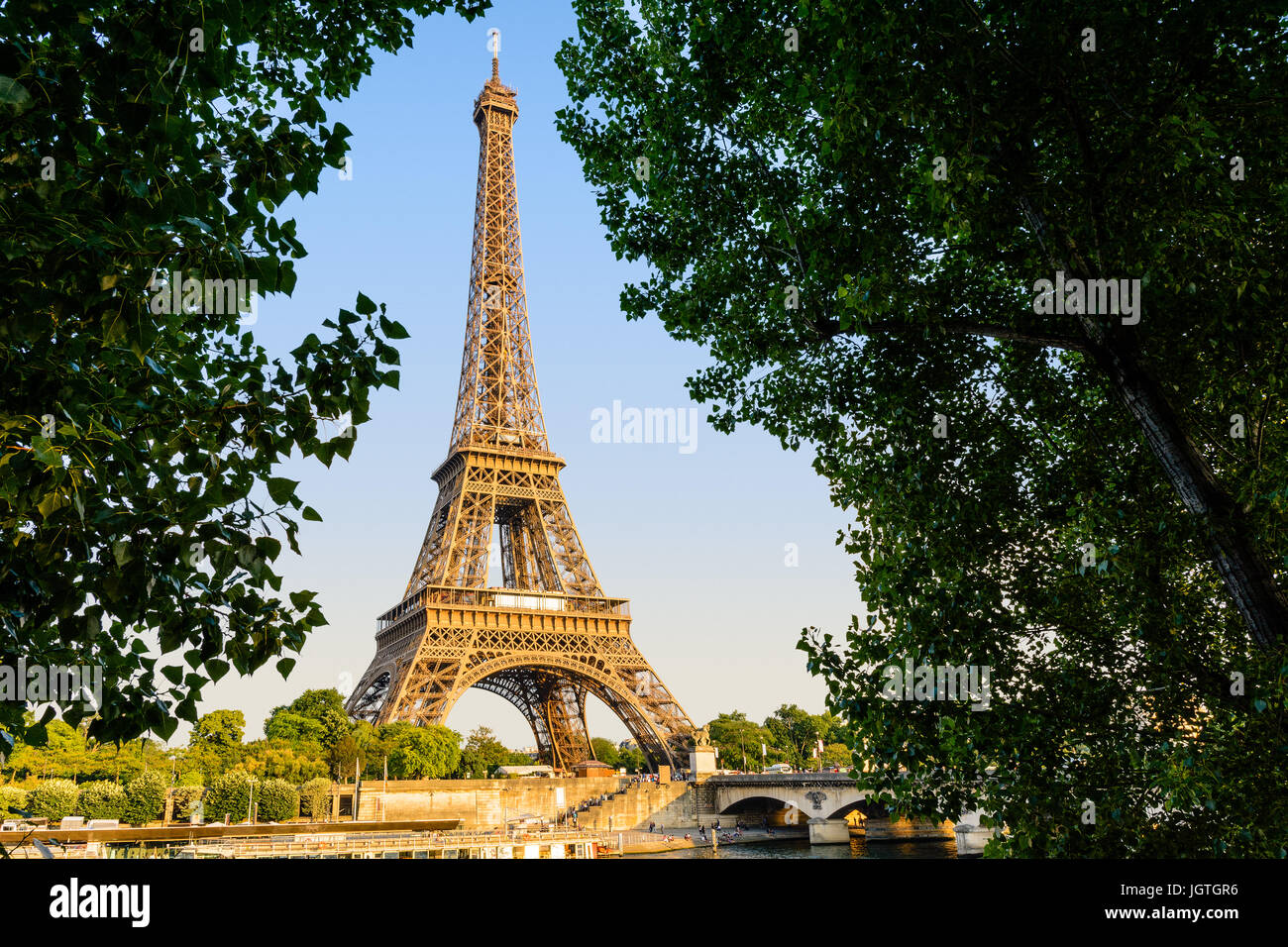 La Tour Eiffel à Paris, France, vu depuis le quai Debilly au coucher du soleil avec le pont d'Iéna, de la Seine et des navettes touristiques au premier plan. Banque D'Images