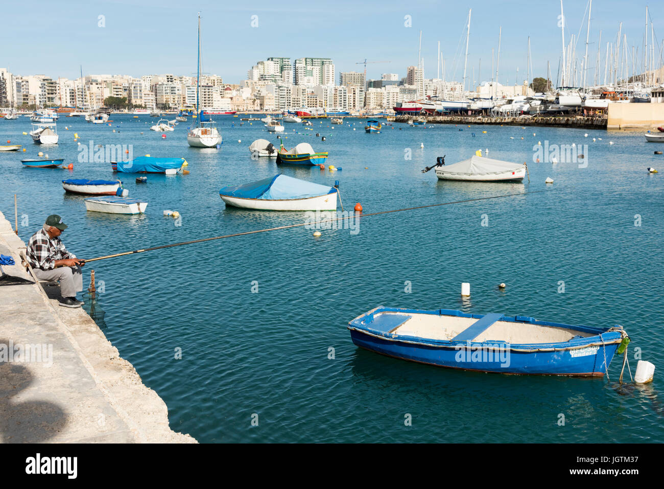 Le port de Marsamuscetto ou port de Marsamxett, Silema avec les bateaux de plaisance et yachts amarrés dans la marina avec un homme depuis le quai de pêche Banque D'Images