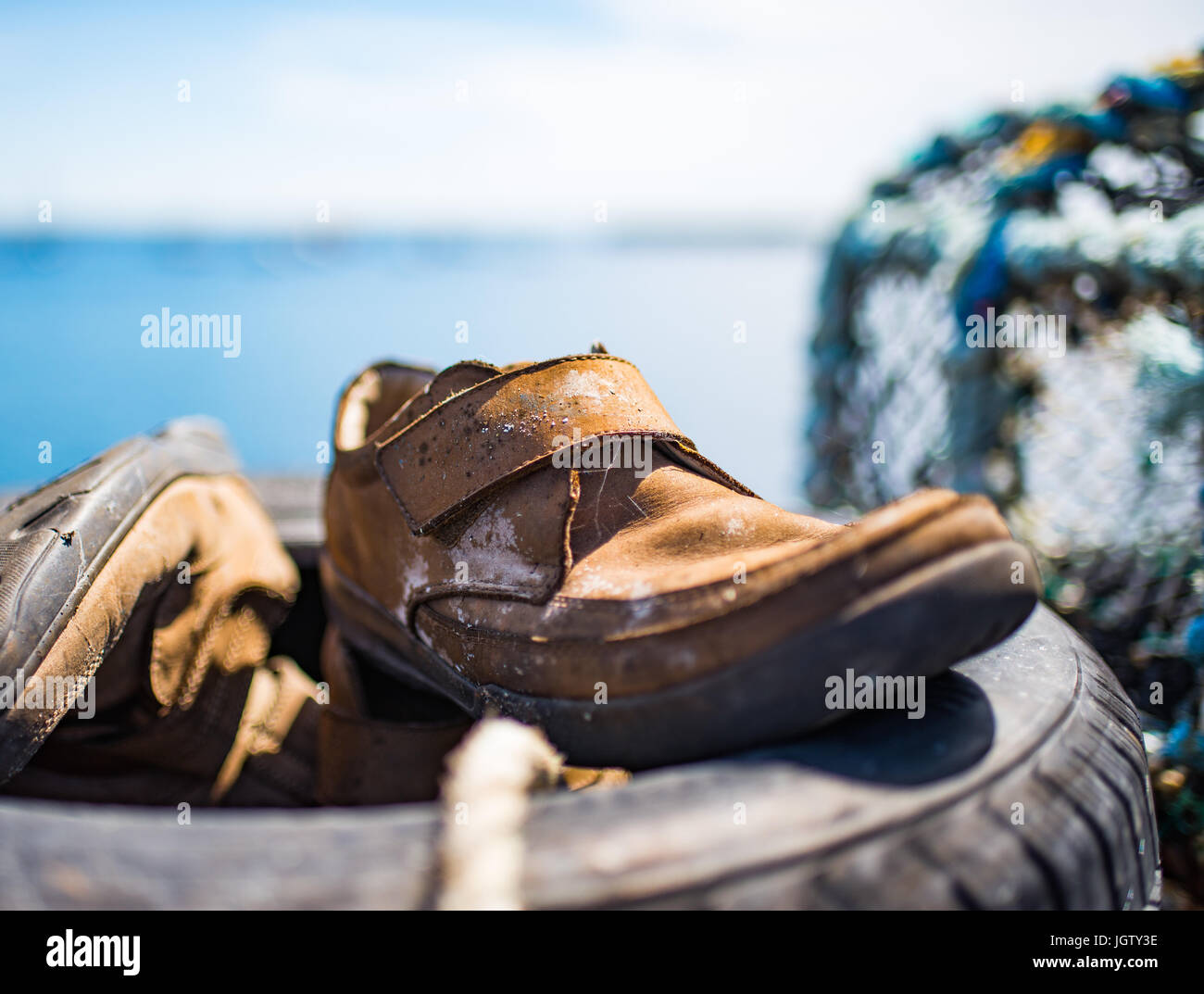 Le vieux cuir chaussures près de la cage à homard Banque D'Images