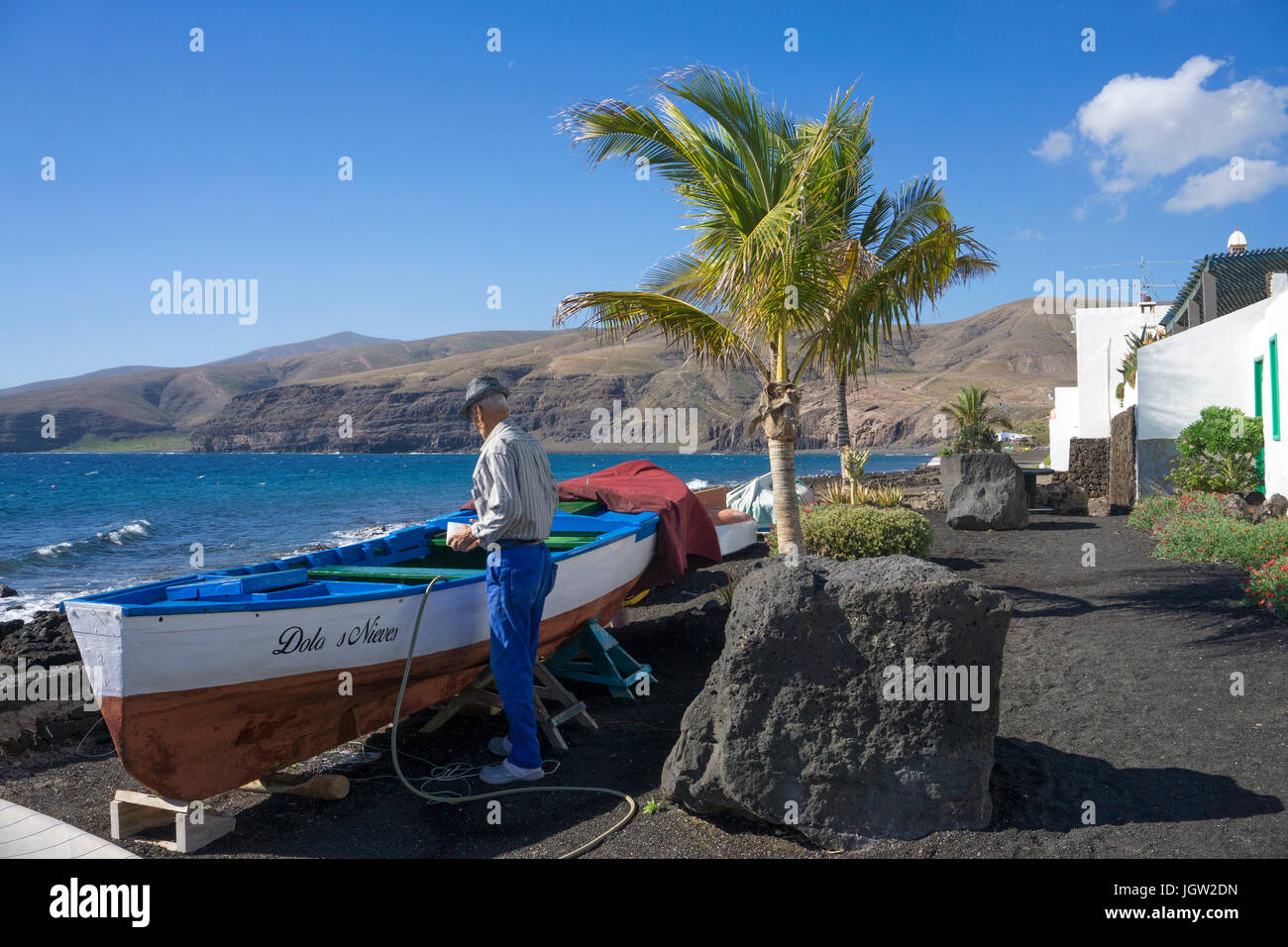 Vieux Pêcheur travailler sur son bateau à la plage, pêche village Playa Quemada, île de Lanzarote, Canary Islands, Spain, Europe Banque D'Images