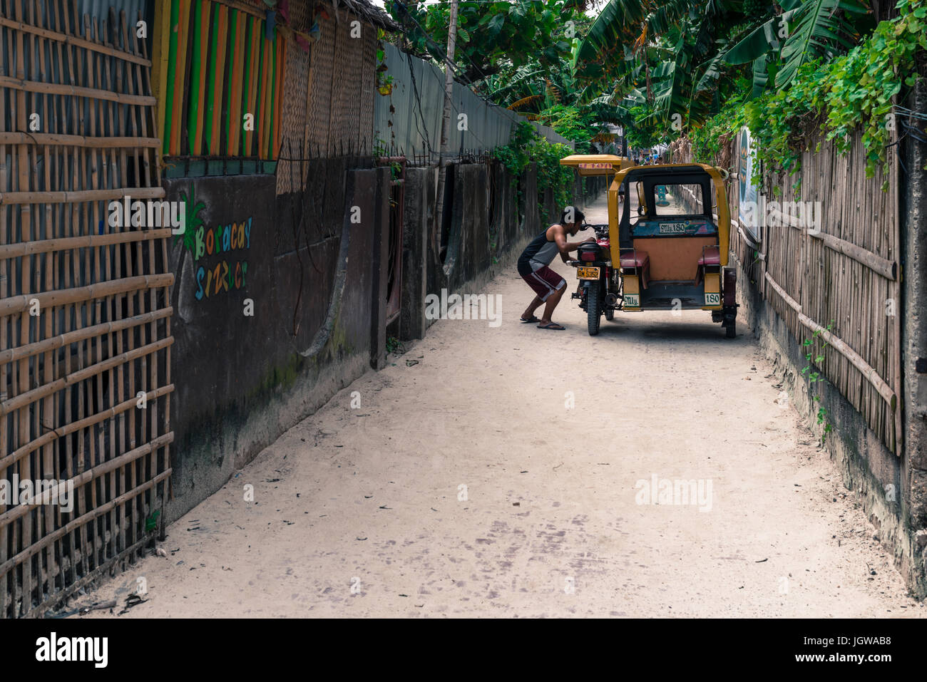 Philippine indigène fixant son tuk tuk dans un passage étroit qui va de Bulabog Beach Banque D'Images