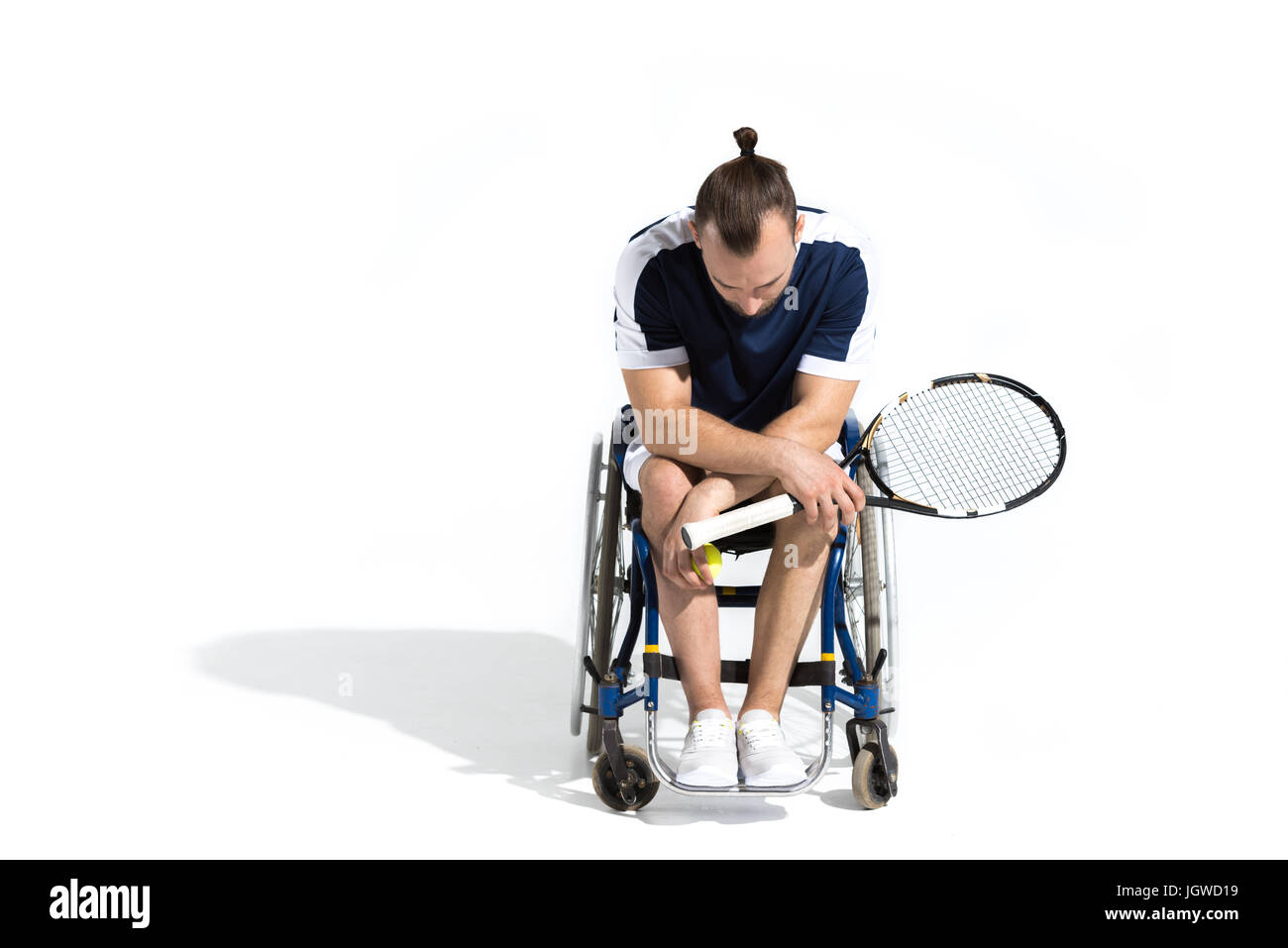 Mobilité jeune homme assis dans un fauteuil roulant et holding tennis racquet isolated on white Banque D'Images