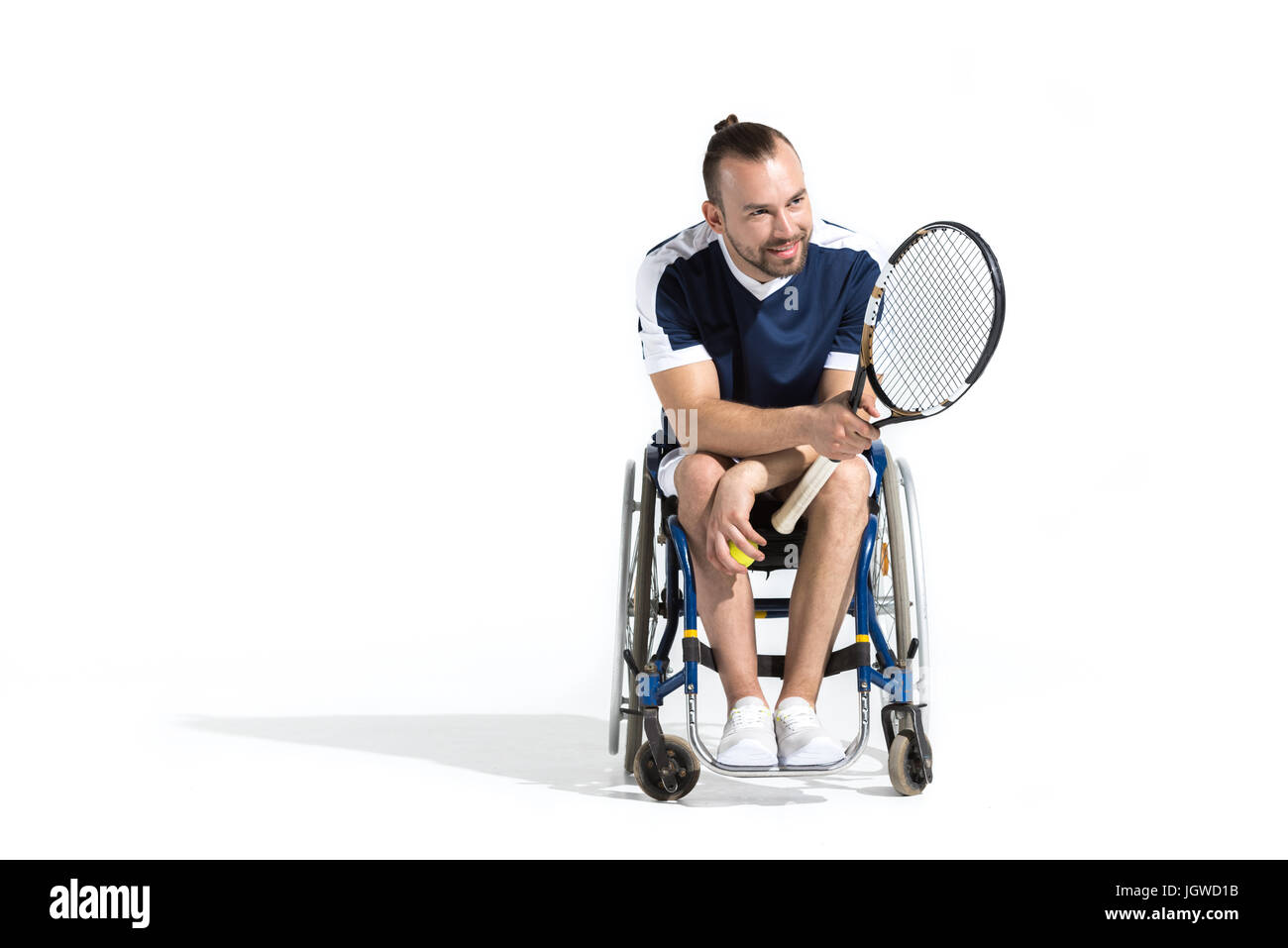 Smiling young man avec raquette de tennis en fauteuil roulant et assis à l'écart Banque D'Images