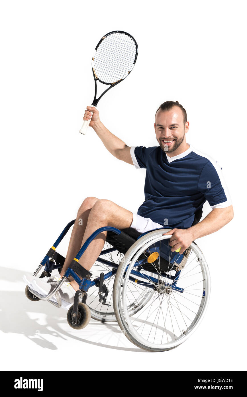 Happy young sportsman in wheelchair holding tennis racquet and smiling at camera Banque D'Images