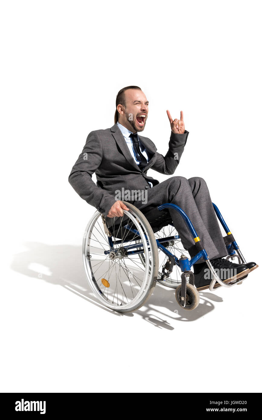 Homme en fauteuil roulant en mobilité excité montrant rock sign isolated on white Banque D'Images