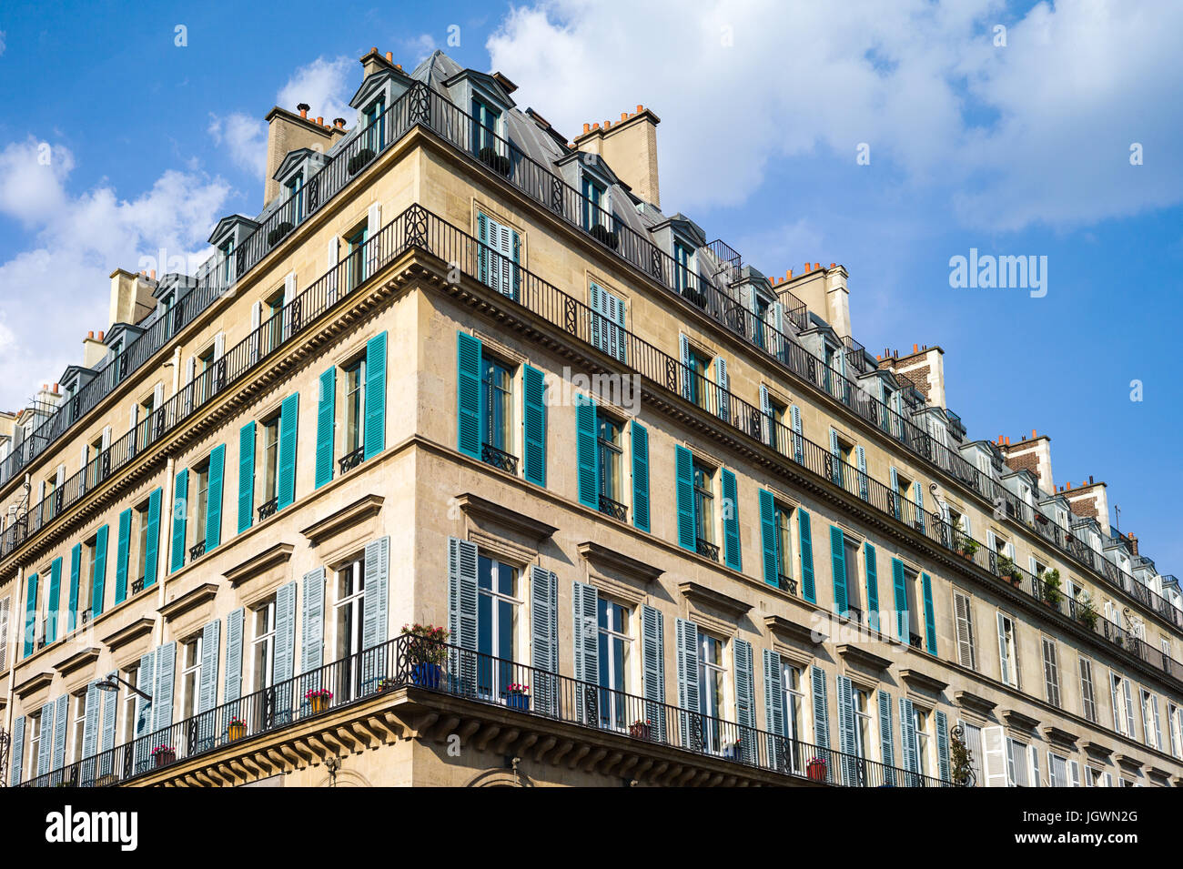 Un immeuble haussmannien typique à Paris avec balcon et volets sous une lumière chaude de fin d'après-midi. Banque D'Images